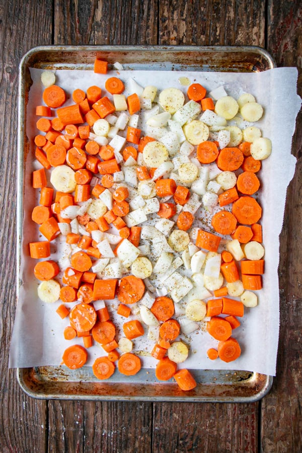 Chopped carrots, onions and garlic on a sheet pan ready to be roasted in the oven.