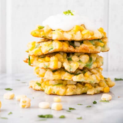 Corn Fritters in a stack with a dollop of sour cream on top.