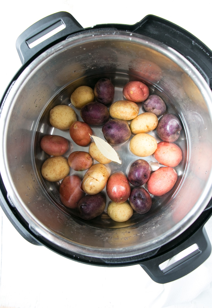 Jewelled coloured little potatoes covered with water in pressure cooker. 