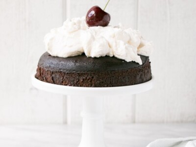 Instant Pot Chocolate Cake with Whipping Cream on a white cake stand.
