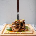 Deeply browned Lemongrass Chicken in a tall stack with a wooden handled knife down the centre.