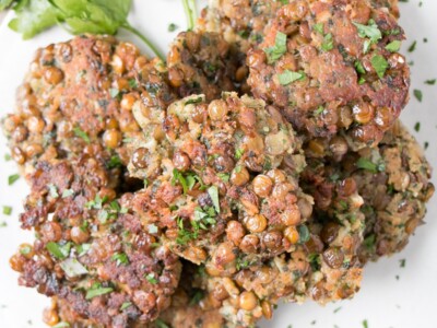 Lentil Fritters piled on a plate with parsley leaves.