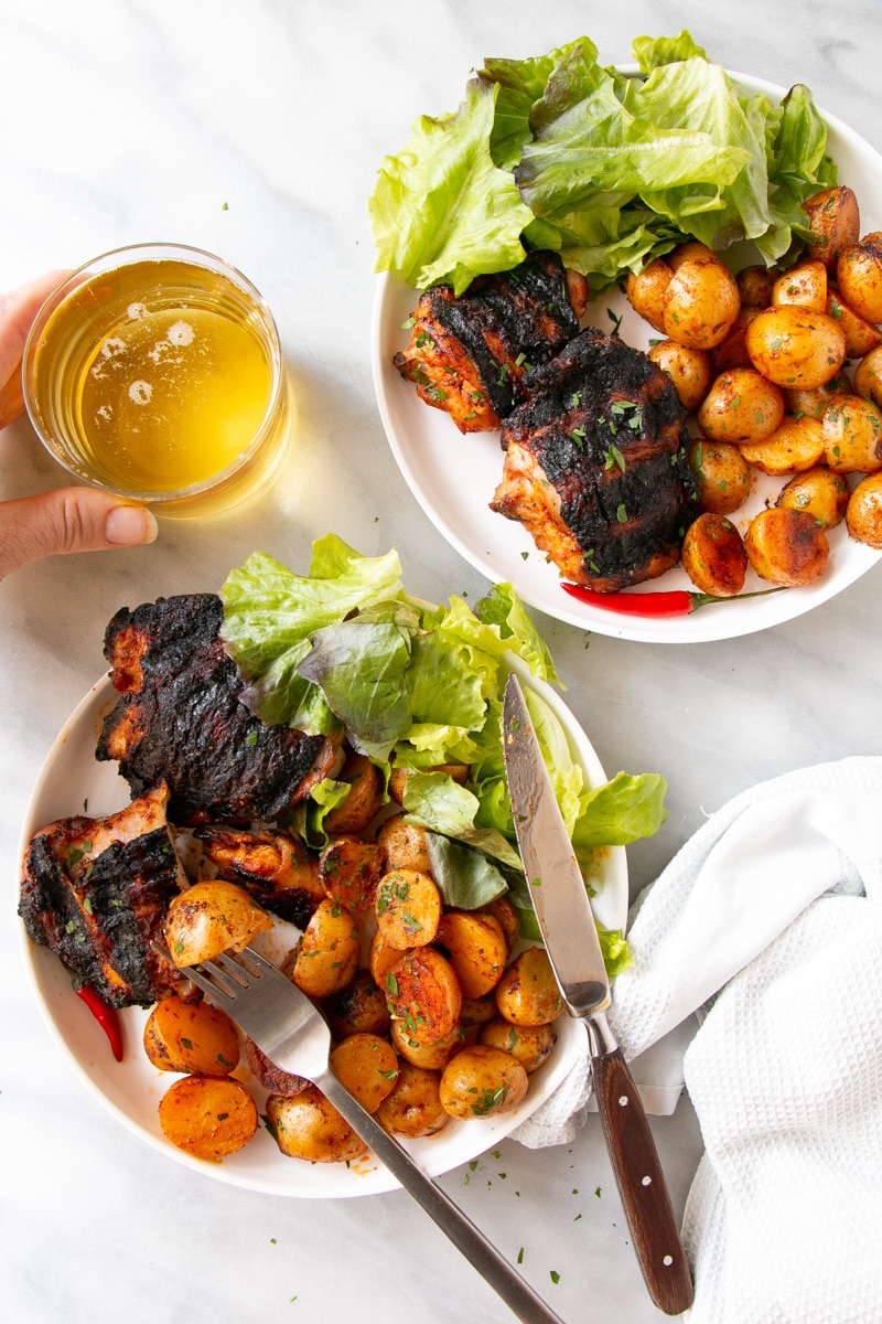Grilled Peri Peri Chicken and Potatoes with a leafy green salad on a white plate. 