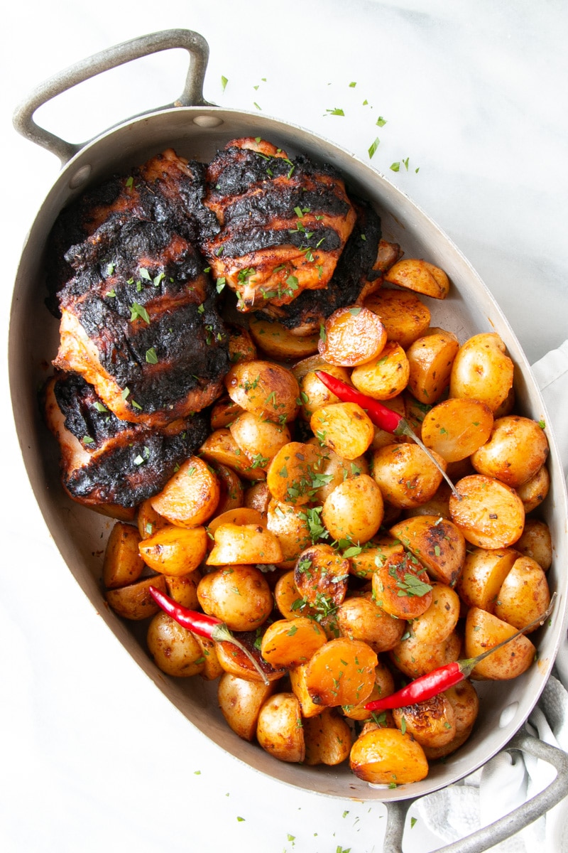 Peri Peri Grilled Chicken and Potatoes in an oval shaped metal dish.