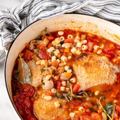 Roasted Chicken Minestrone Soup with herbs in a white Dutch Oven.