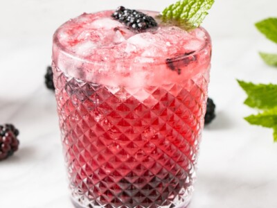 Blackberry Mojito in a textured glass with blackberries, lime and mint.