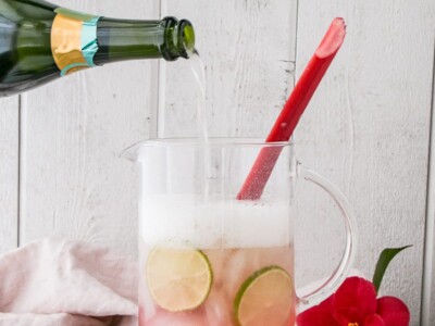 sparkling rhubarb margarita in a pitcher with sparkling wine being added in.