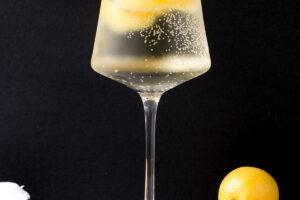 White wine spritzer in a tall wine glass with lemon rind in it.